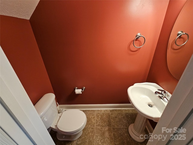 bathroom featuring a sink, baseboards, tile patterned floors, and toilet