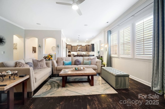 living area featuring baseboards, ceiling fan, crown molding, wood finished floors, and arched walkways