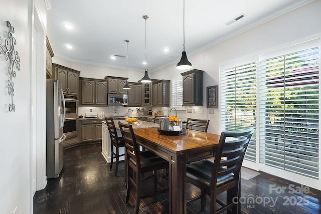 dining room with crown molding, dark wood finished floors, and visible vents