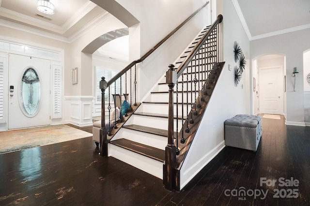 entrance foyer featuring stairway, ornamental molding, arched walkways, and hardwood / wood-style floors
