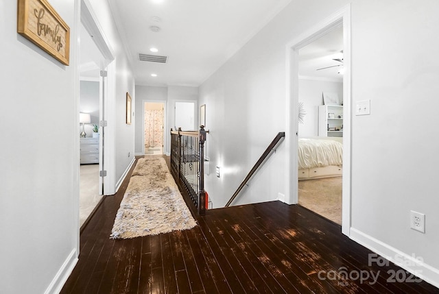 corridor with visible vents, an upstairs landing, baseboards, and hardwood / wood-style floors