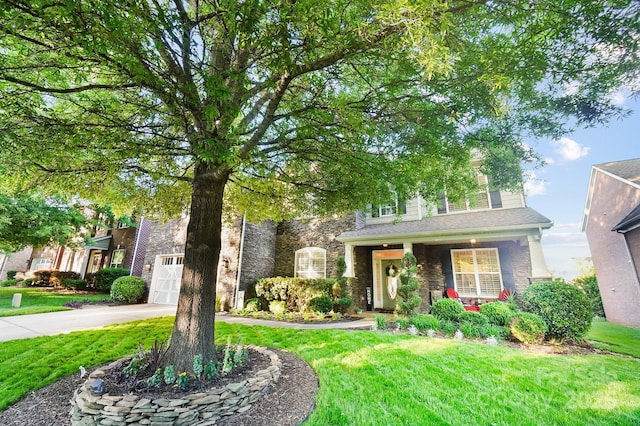 obstructed view of property featuring stone siding, a front yard, driveway, and covered porch