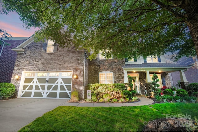 view of front of house featuring stone siding, concrete driveway, and a yard