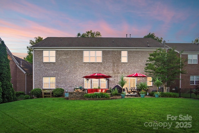 back of property at dusk featuring brick siding