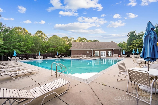 community pool with a patio and fence