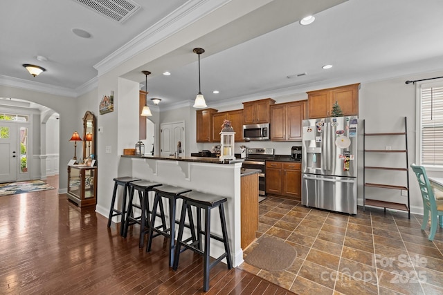 1004 Craven St, Indian Trail, NC 28079 - kitchen featuring appliances with stainless steel finishes, dark countertops, brown cabinetry, arched walkways, and ornamental molding