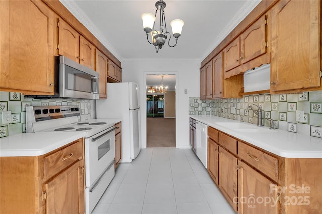 kitchen featuring an inviting chandelier, white appliances, light countertops, a sink, and decorative light fixtures