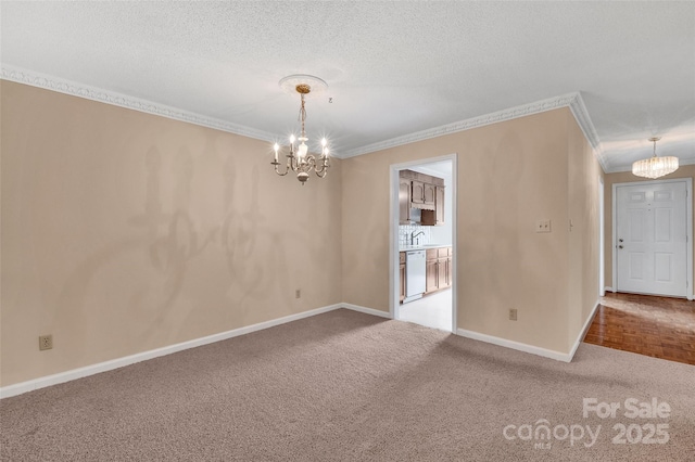 carpeted empty room with crown molding, baseboards, a textured ceiling, and a chandelier