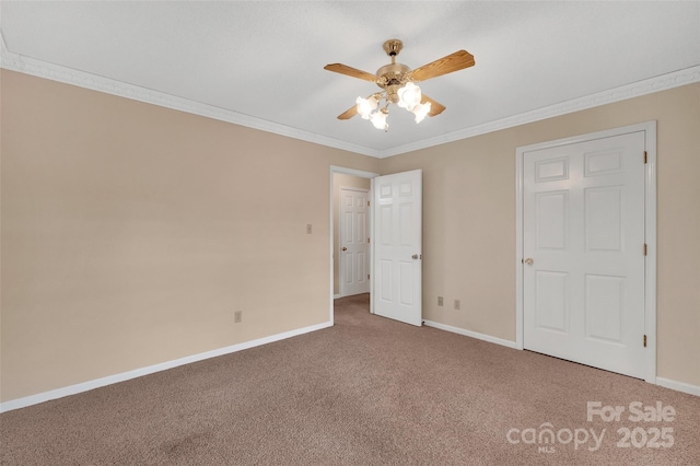 unfurnished bedroom with baseboards, ornamental molding, carpet, and a ceiling fan