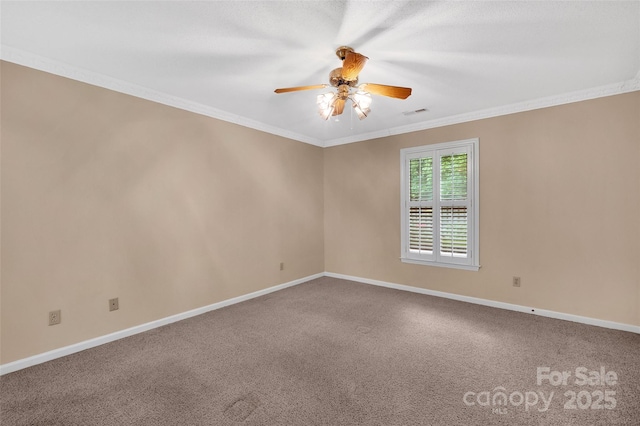 carpeted spare room featuring crown molding, baseboards, ceiling fan, and visible vents