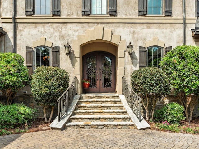 view of exterior entry with stucco siding, french doors, and stone siding
