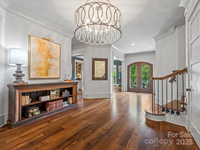 entryway with a chandelier, french doors, baseboards, wood finished floors, and ornamental molding