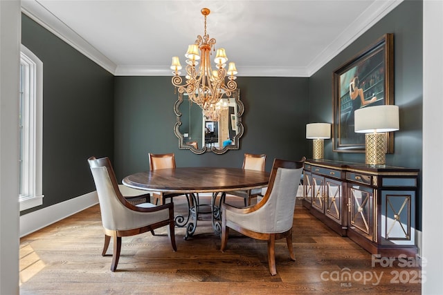 dining area featuring baseboards, ornamental molding, wood finished floors, and a chandelier