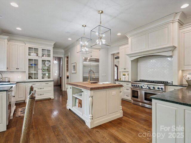 kitchen featuring backsplash, high end appliances, a chandelier, and wooden counters