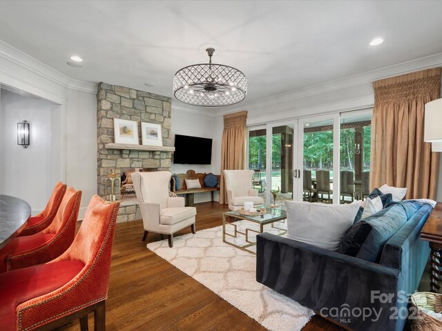 living room with a fireplace, wood finished floors, a chandelier, ornamental molding, and recessed lighting
