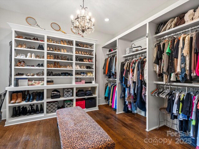spacious closet with wood finished floors and a notable chandelier
