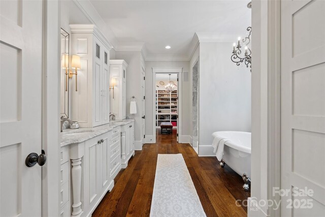 full bathroom with crown molding, a freestanding bath, double vanity, a chandelier, and baseboards