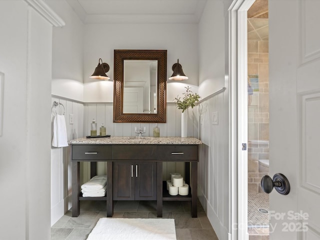 bathroom with wainscoting, vanity, and a decorative wall