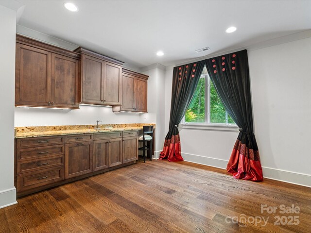 kitchen with a sink, baseboards, dark wood-type flooring, and visible vents