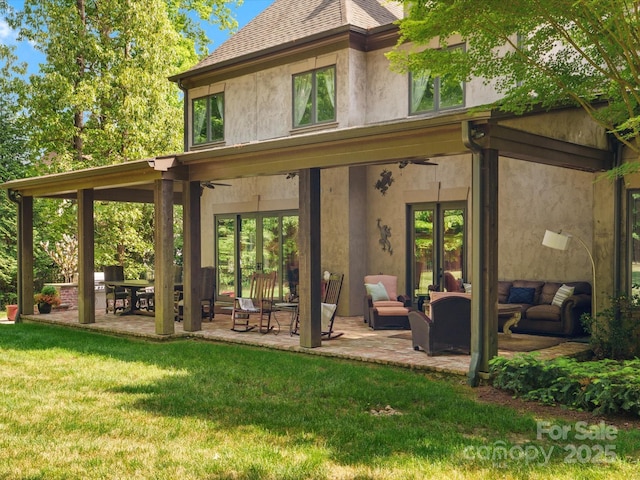 rear view of property with a lawn, stucco siding, a patio area, and outdoor lounge area
