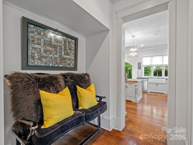 living area with wood finished floors, baseboards, a notable chandelier, ornamental molding, and recessed lighting
