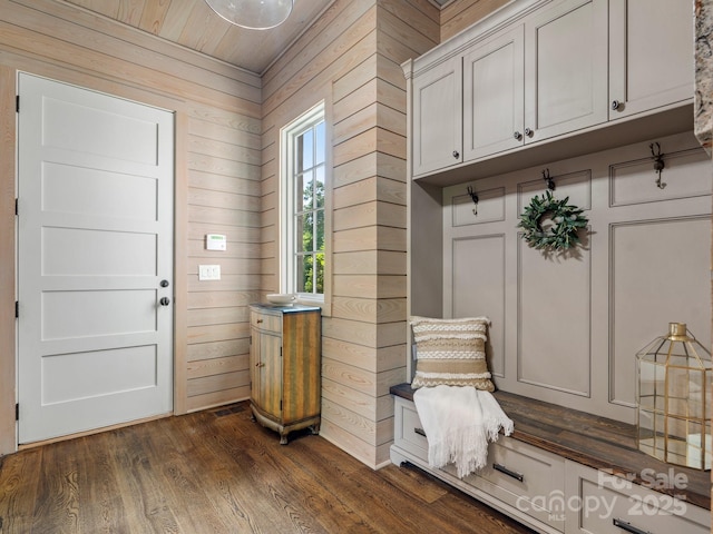 foyer entrance with wooden walls, dark wood finished floors, and wood ceiling