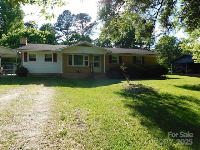 view of front facade with a front lawn, driveway, a chimney, and a carport