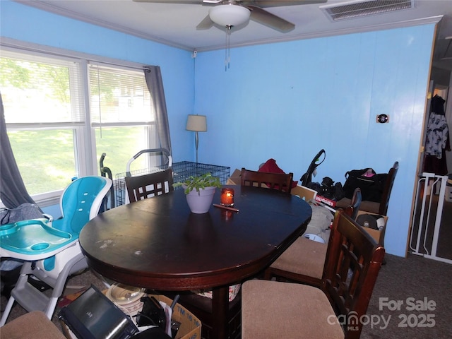 carpeted dining area featuring crown molding, a ceiling fan, and visible vents