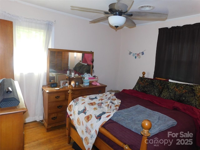 bedroom featuring ornamental molding, light wood-style flooring, and ceiling fan
