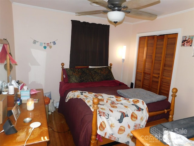 bedroom featuring a ceiling fan, ornamental molding, a closet, and wood finished floors