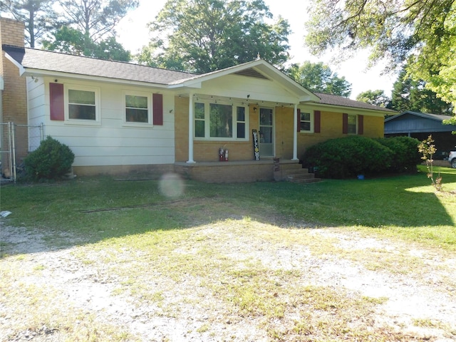 ranch-style home with covered porch, brick siding, a chimney, and a front yard
