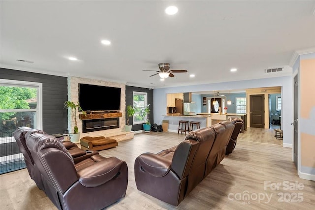 living room with visible vents, baseboards, crown molding, and light wood-type flooring