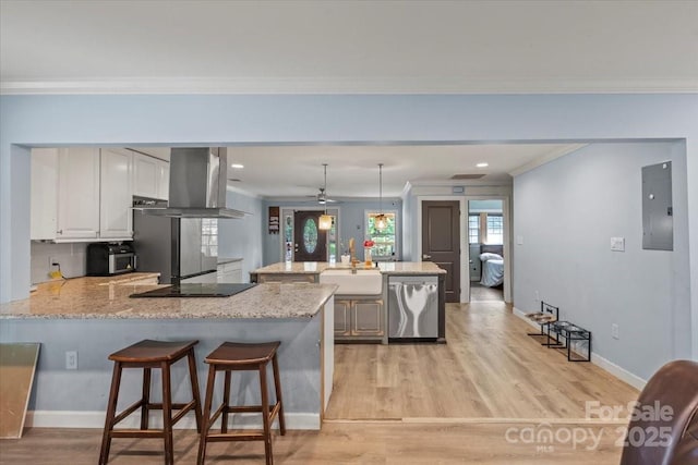 kitchen with electric panel, a sink, a peninsula, ornamental molding, and extractor fan