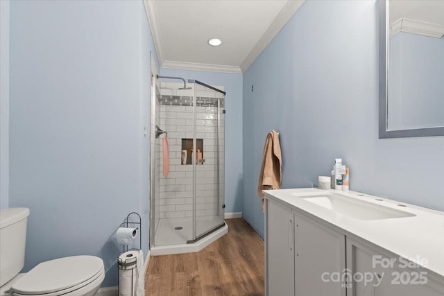 bathroom featuring a shower stall, wood finished floors, vanity, toilet, and ornamental molding