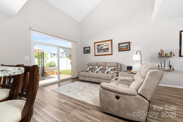 living room with baseboards, high vaulted ceiling, and wood finished floors
