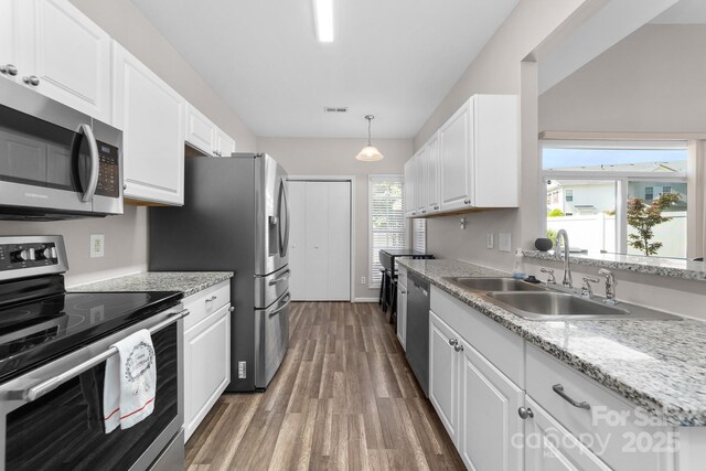 kitchen featuring a sink, appliances with stainless steel finishes, wood finished floors, and white cabinets