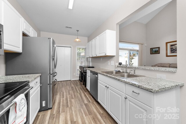 kitchen featuring a healthy amount of sunlight, appliances with stainless steel finishes, white cabinetry, a sink, and light wood-style flooring