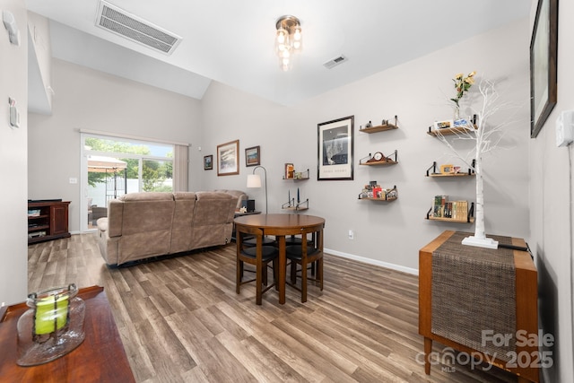 dining area featuring baseboards, visible vents, wood finished floors, and vaulted ceiling