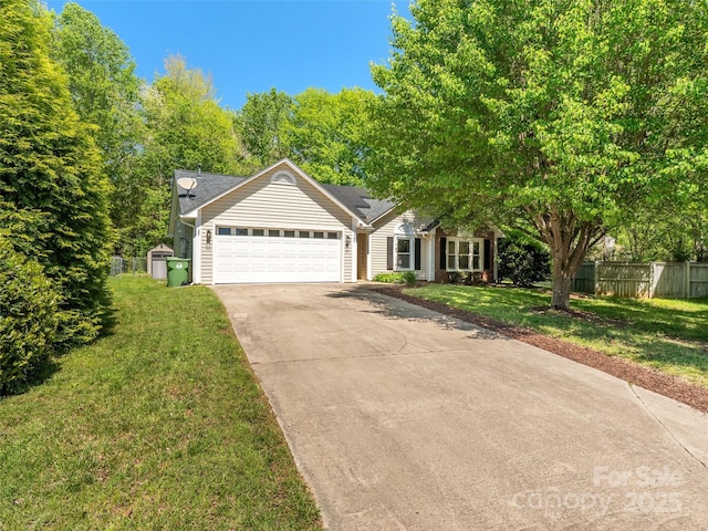 view of front of property with fence, a front yard, roof mounted solar panels, an attached garage, and driveway