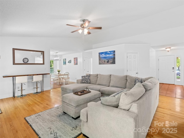 living room with baseboards, ceiling fan with notable chandelier, and wood finished floors