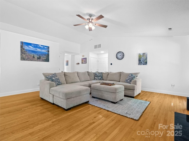 living room with baseboards, a ceiling fan, vaulted ceiling, and visible vents