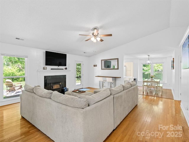living area featuring ceiling fan, a wealth of natural light, light wood-style flooring, and a fireplace