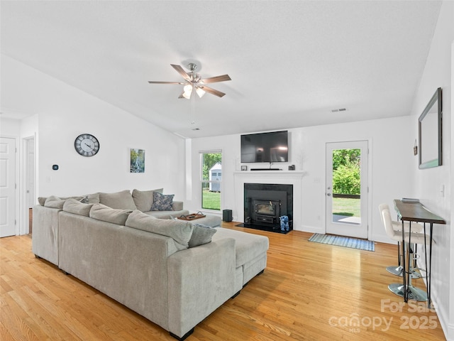 living room with light wood-type flooring, a ceiling fan, a wealth of natural light, and visible vents