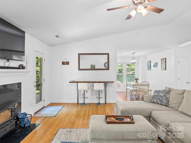 living room featuring visible vents, a healthy amount of sunlight, ceiling fan with notable chandelier, and wood finished floors