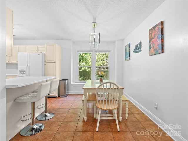 dining room featuring baseboards, a textured ceiling, and light tile patterned floors