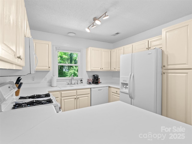 kitchen with white appliances, a textured ceiling, a sink, and light countertops