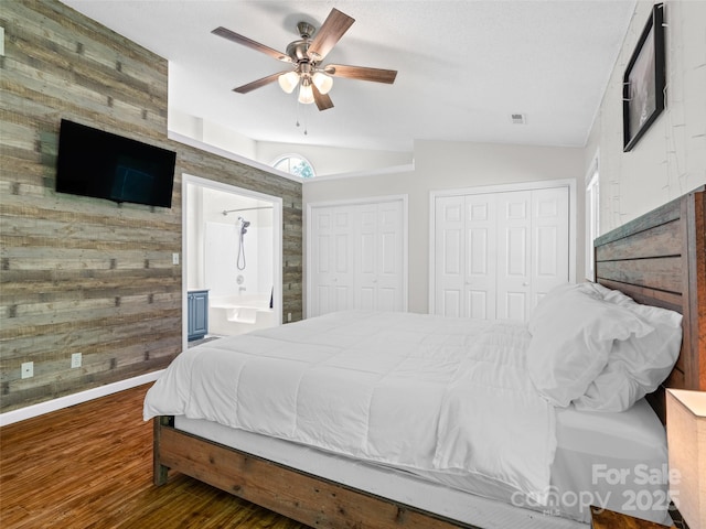 bedroom with wooden walls, multiple closets, wood finished floors, and lofted ceiling