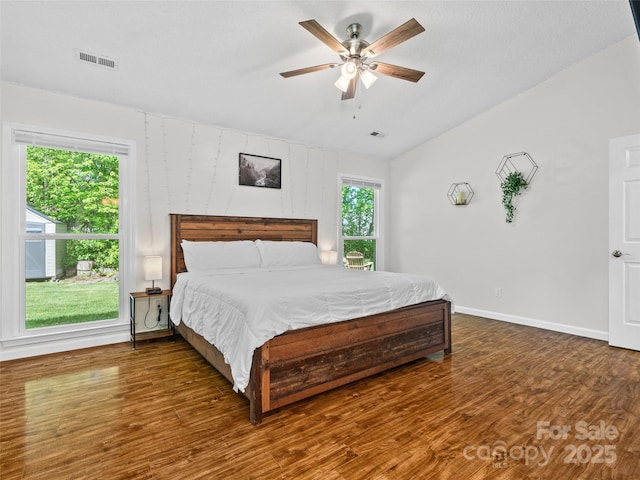 bedroom with baseboards, lofted ceiling, wood finished floors, and visible vents