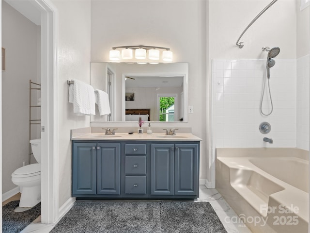 full bathroom featuring double vanity, toilet, baseboards, and a sink