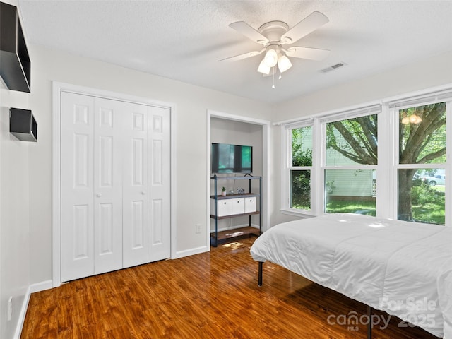 bedroom featuring baseboards, visible vents, wood finished floors, and a closet